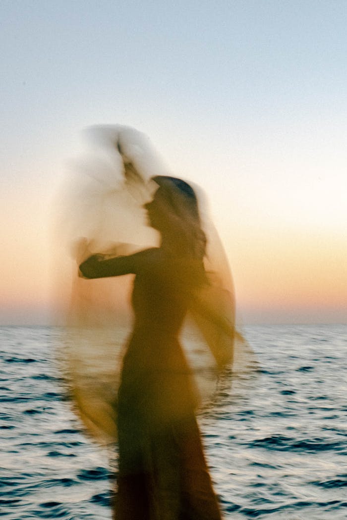 Blurred silhouette of a woman by the sea in Odessa at sunset, capturing motion and tranquility.